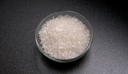 Bowl and spoon with sugar on wooden background.
