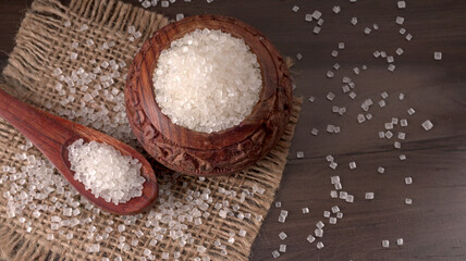 Bowl and spoon with sugar on wooden background.