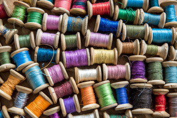 The background is made of colorful threads on wooden vintage reels. Skeins of colored thread. Top view.