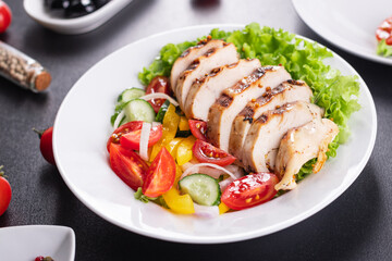 salad grilled chicken breast vegetables tomato, cucumber, onion, pepper outdoor meal snack on the table copy space food background rustic. top view keto or paleo diet