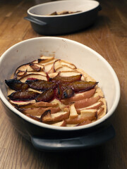 Cake with plum and apples in a baking dish