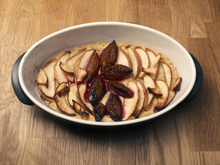 Cake with plum and apples in a baking dish