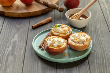 Selective focus of baked peaches with cinnamon, almond petals, cream cheese, and honey on a wooden...
