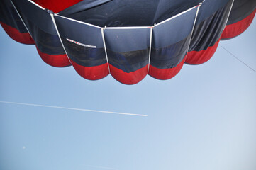 Obraz premium Inflated balloon dome. A view of a hot air balloon, blue sky and a white trail from a flying plane.