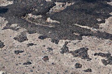 a bad asphalt road that has been repaired many times
