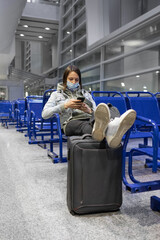 European woman at the airport waiting to board her flight, flight and boarding delays, restrictions on international airline flights, Caucasian woman bored at the airport in the waiting area