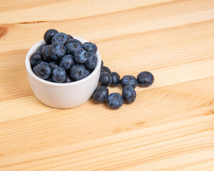 Fresh blueberry in white dish on wooden background