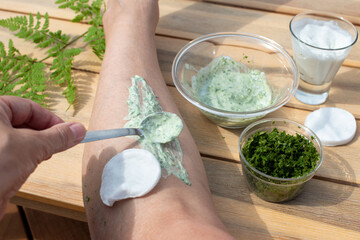Female hand applying healing cream with Wood Fern leaves and yogurt on her leg