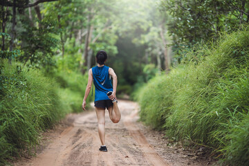 Behind active young woman in sportswear stretching before trail running in the rural road. Sporty girl warming up for running. Sport and healthy lifestyle.