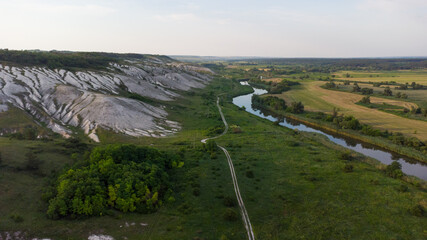 Aerial view of white chalk mountains and hills and green fields. A river flows nearby. Dvorichanskyi National Nature Park, Kharkiv region, Ukraine