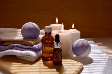 Spa aromatherapy still life with aroma oil bottle, purple bath bombs and lit candles. Bath accessories on wooden background for massage salon, skin care products or relaxation. Trendy fall scene - obrazy, fototapety, plakaty