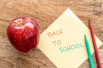 Back to school concept with apple, colored pencils over wooden background.