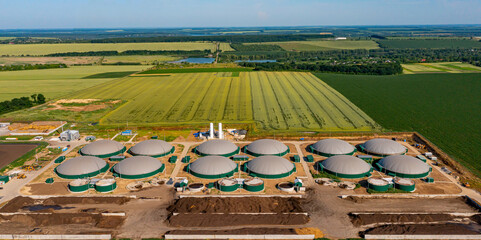 Green biogas plant storage tanks. Aerial view over biogas plant and farm in green fields. Renewable energy from biomass. Modern agriculture concept