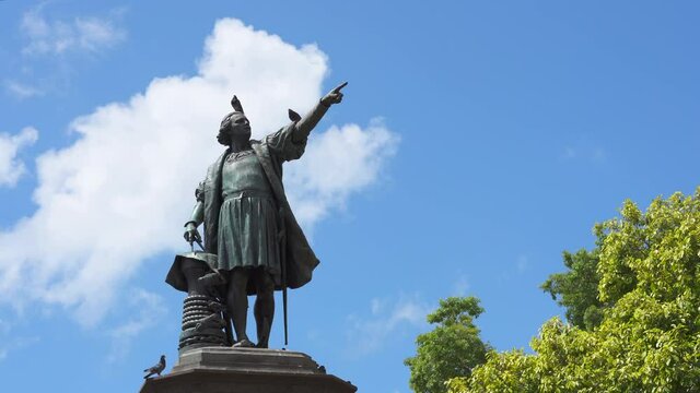 Dominican Republic, Santo Domingo - August 7, 2021: Monument to Christopher Columbus against a blue sky in Colonial City. Pigeons sitting on a statue