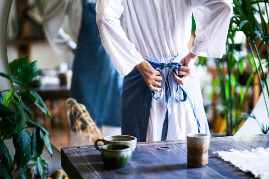 Women's hands tie an apron before the process, close-up, frontal photography, back view, natural light