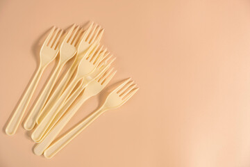 Disposable plastic forks on beige background with copy space.