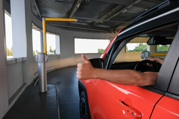 A man's hand with a thumb up near the car when entering an underground parking lot. Parking security system