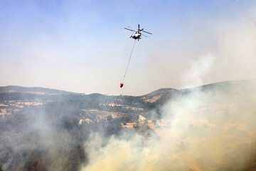 fire fighting helicopter leaves water to the forest fire
