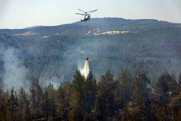 fire fighting helicopter leaves water to the forest fire