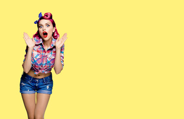 Unbelievable news! Excited surprised, very happy red purple haired woman. Pin up syle girl with opened mouth and raised hands. Retro and vintage concept. Yellow background with mock up copy space.