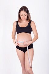 Young pregnant woman measuring her belly and smiling. The anticipation of motherhood