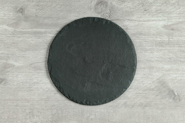 Round shaped slate serving board on gray background. Top view