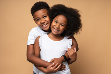 I love you. Waist up portrait view of the lovely multiracial boy embracing with tenderness his curly sister and looking at the camera. Family relationships concept