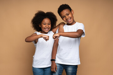 Great team. Portrait of positive brother and sister hugging and bumping with fists with toothy...