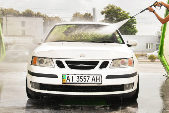 Chernigov, Ukraine - July 24, 2021: A man washes a car. Saab car at the car wash. White Saab 9-3 at a self-service car wash
