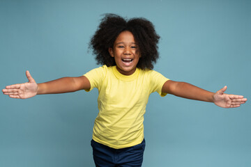 Come here, free hugs. Portrait of lovely good-natured little girl with curly hair in yellow T-shirt...