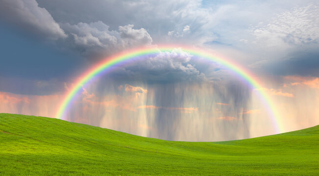 Rain over rural landscape with amazing rainbow at sunset