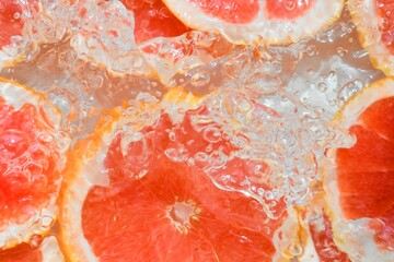 Slices of grapefruit in water on white background. Grapefruit close-up in liquid with bubbles....