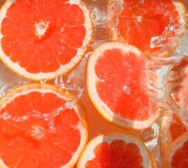Slices of grapefruit in water on white background. Grapefruit close-up in liquid with bubbles....