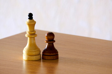 Chess wooden pieces of black and white color, queen and pawn on a wooden table. The concept of success in sports or business. Assistant manager