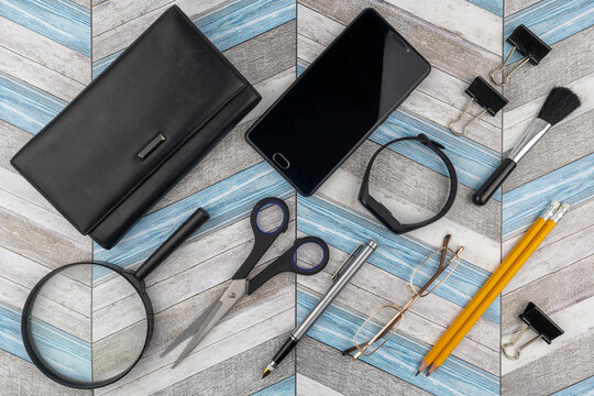 Conceptual office or business flat lay background on a zig-zag wood pattern with reading glasses, magnifying glass, smartphone and stationery supplies