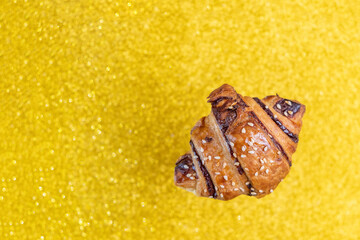 Chocolate croissant on glitter golden background with copy space.
