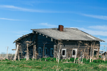 An old one-story, leaning village house made of wood is being destroyed. Russian village.