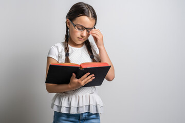 Lovely little girl standing and holding book over white background