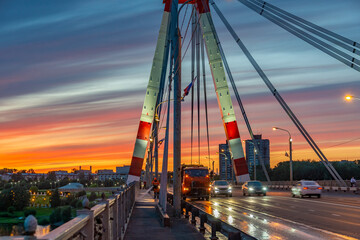 Fototapeta na wymiar Russia, Cherepovets June 27, 2020 beautiful colored sky at sunset on the background of a bridge and a car in soft focus, watering the street in order to prevent against the virus.