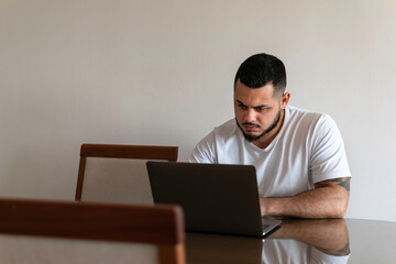 Latino man looking with an angry face at a laptop screen