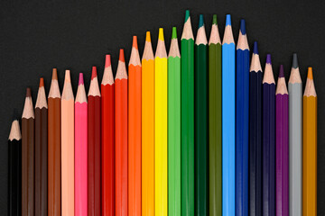 Crayons. Colored pencils on black cardboard background. Top view. Education concept. High quality photo 