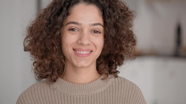 close up portrait smiling young brunette with curly hair posing looking camera joyful woman at home slow motion