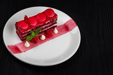 Plate with piece of delicious red velvet cake on black wooden background, food and drink concept