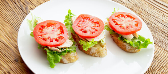 open sandwiches with tomatoes, lettuce, cheese, and chicken