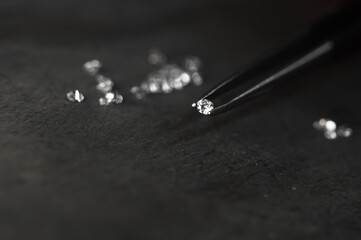 Diamond in tweezers. Craft jewelery, professional tools. Ring repairing. Macro shot.