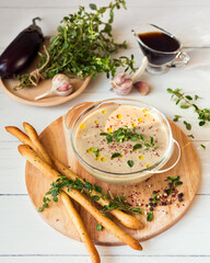 Vegetable puree soup on a white wooden background. Eggplant cream soup with garlic and thyme. Balsamic vinegar dressing. Serving an autumn dish. Vegetarian food. Vegan cuisine. Grissini Breadsticks
