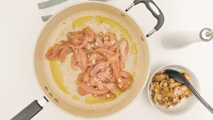 Fresh raw chopped breast chicken meat marinated with garlic seasoning close up on frying pan