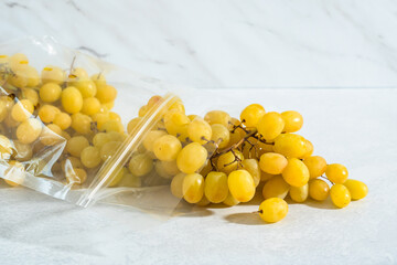 The grape cluster close up in plastic bag on light marble background