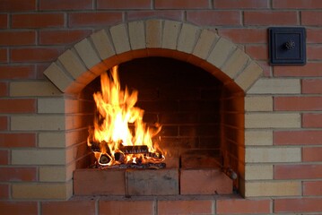 Fototapety  Burning firewood with fire in a stone fireplace made of bricks.