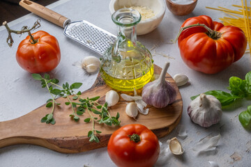 Preparing an Italian meal with a chopping board, tomatoes, garlic, oil, basil, cheese and salt